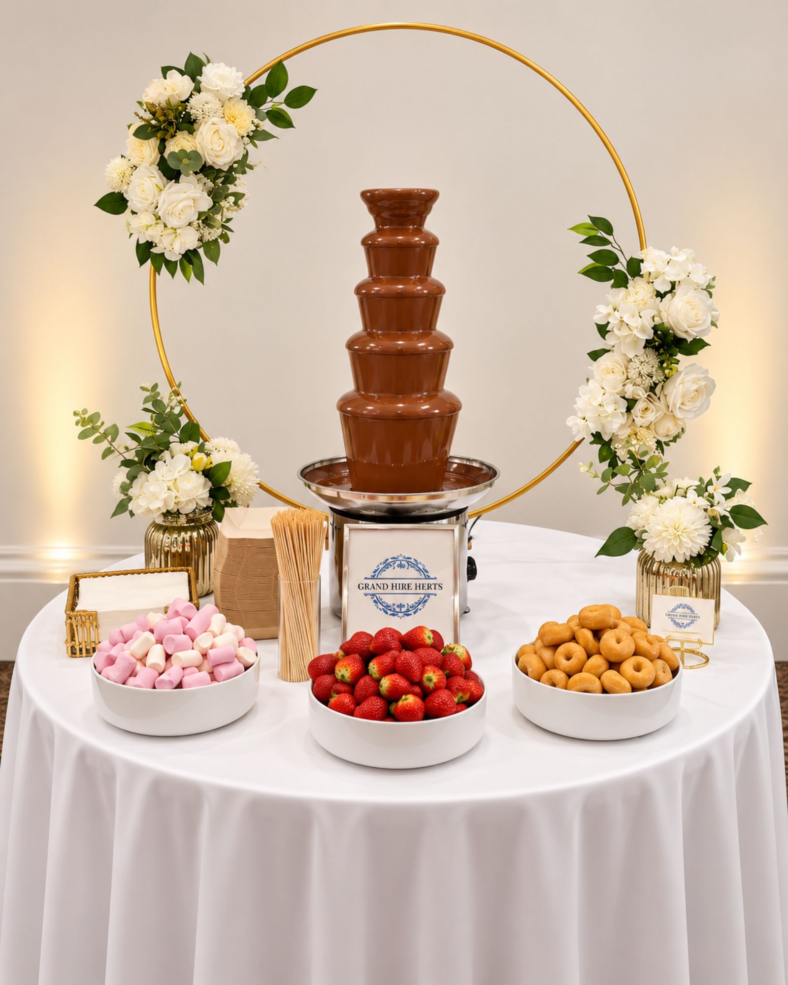 Chocolate fountain display with flowers, strawberries and sweet treats.
