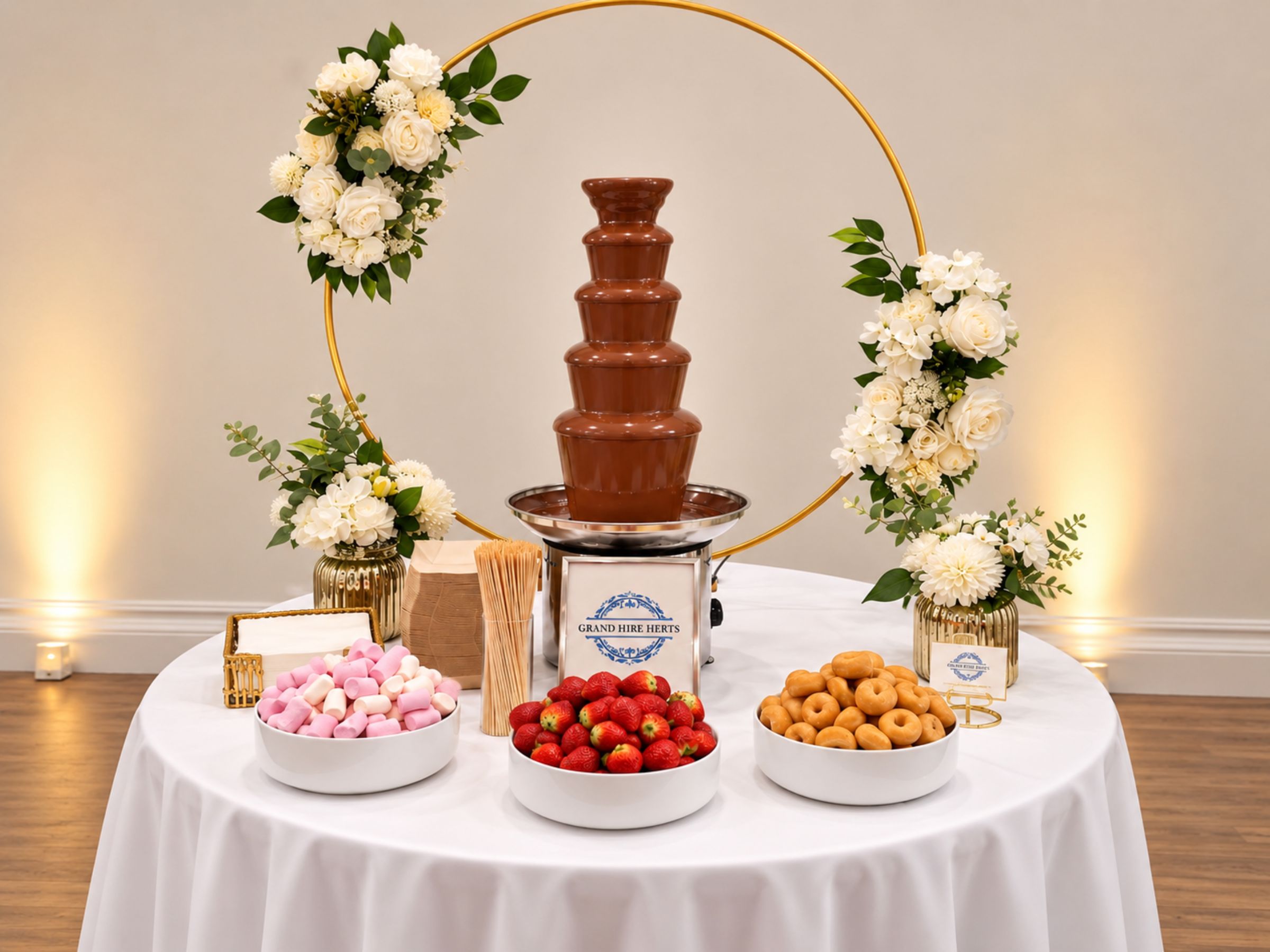 Chocolate fountain display with flowers, strawberries and sweet treats.