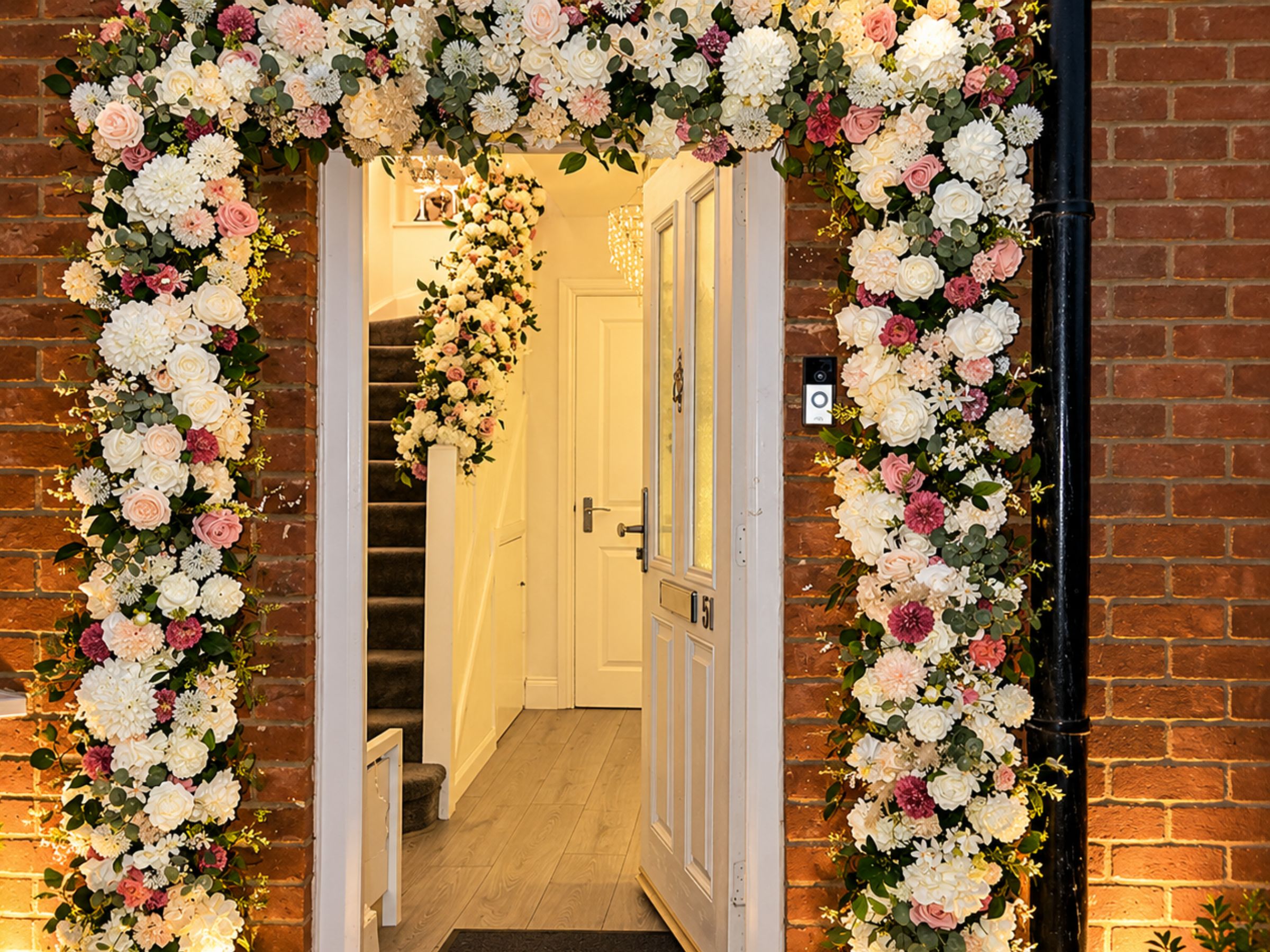 Home entrance framed with pink and white flowers and draped fabric.